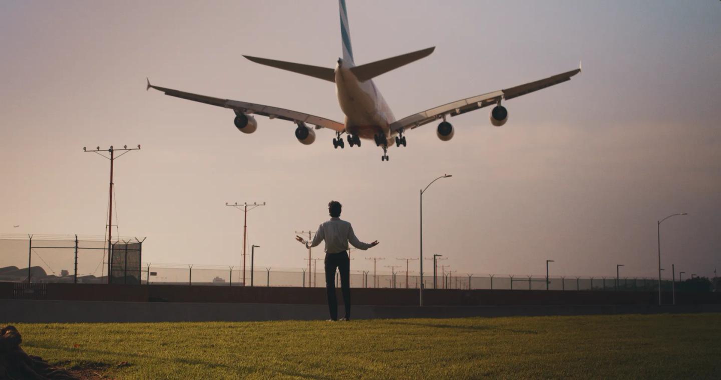 a person is standing in front of an airplane taking off