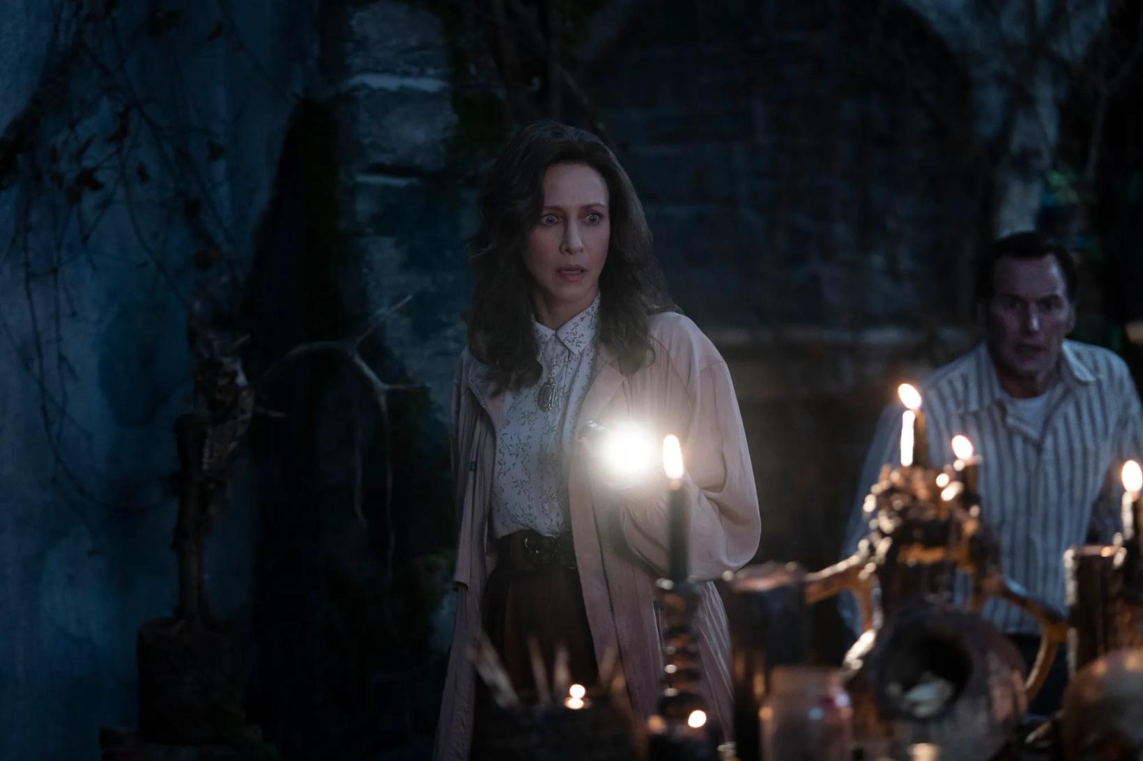 Vera Farmiga standing in a cave with a man sitting in the back