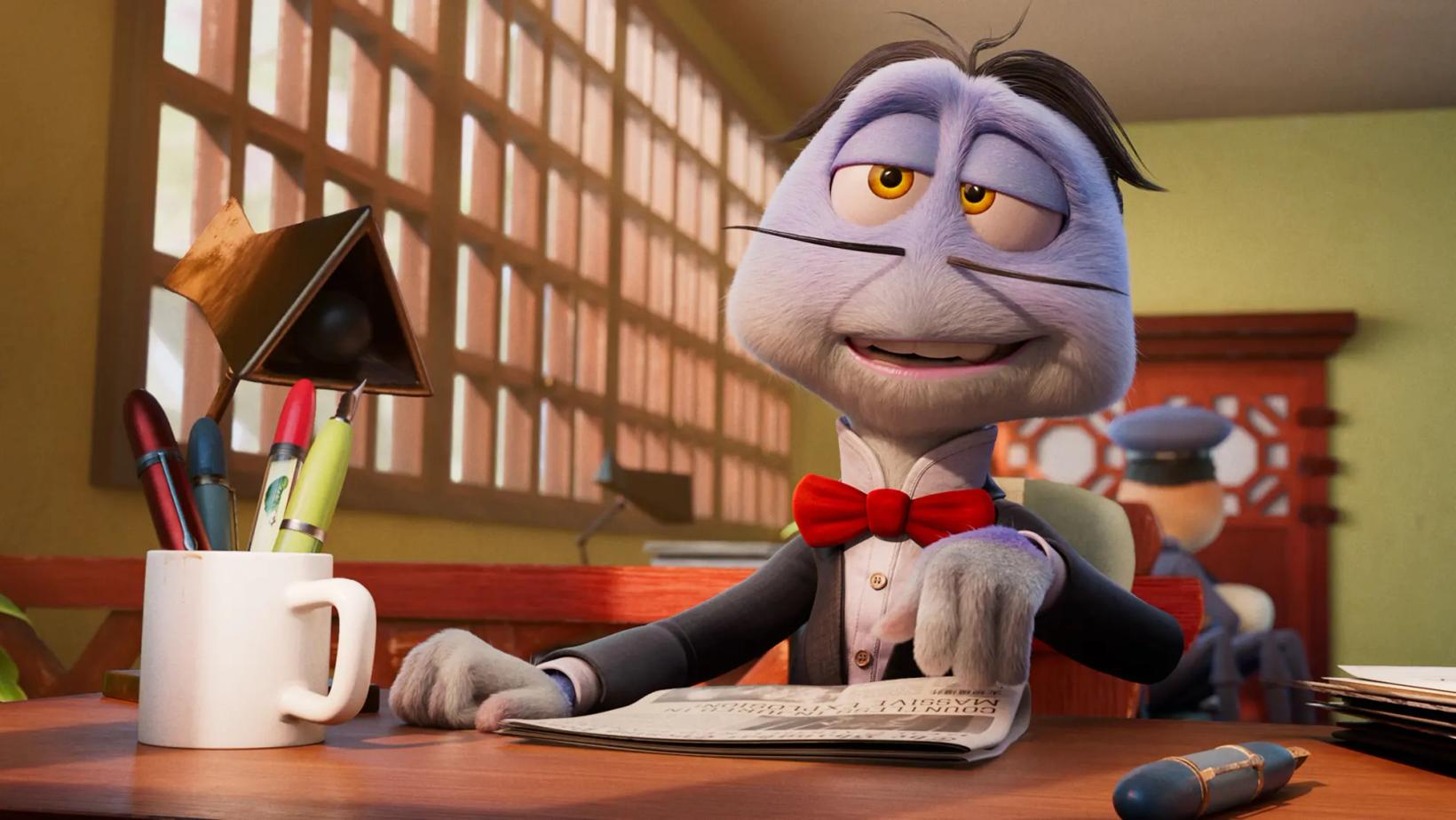 a person in a garment sitting at a desk with a mug and a book