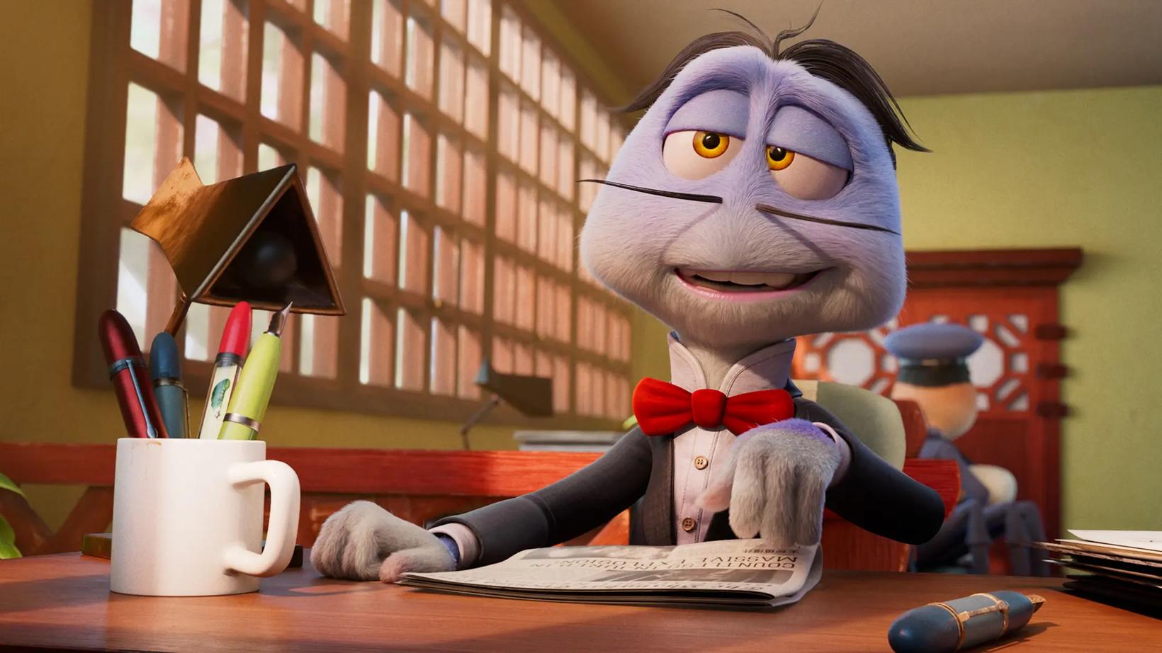 a person in a garment sitting at a desk with a mug and a book