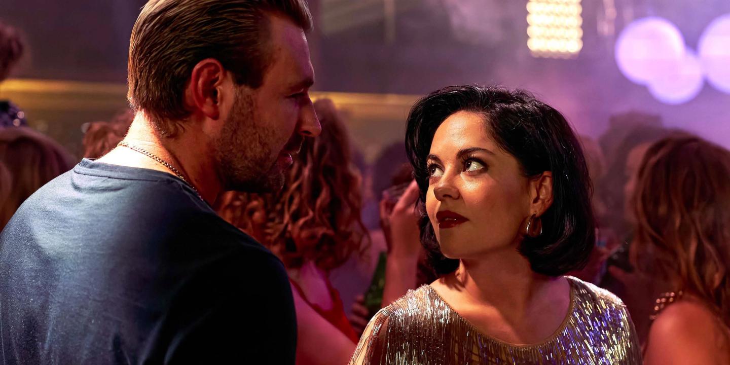 James McArdle og Sarah Greene ser på hverandre på et fargerikt dansegulv i Sexy Beast (serie, 2024).