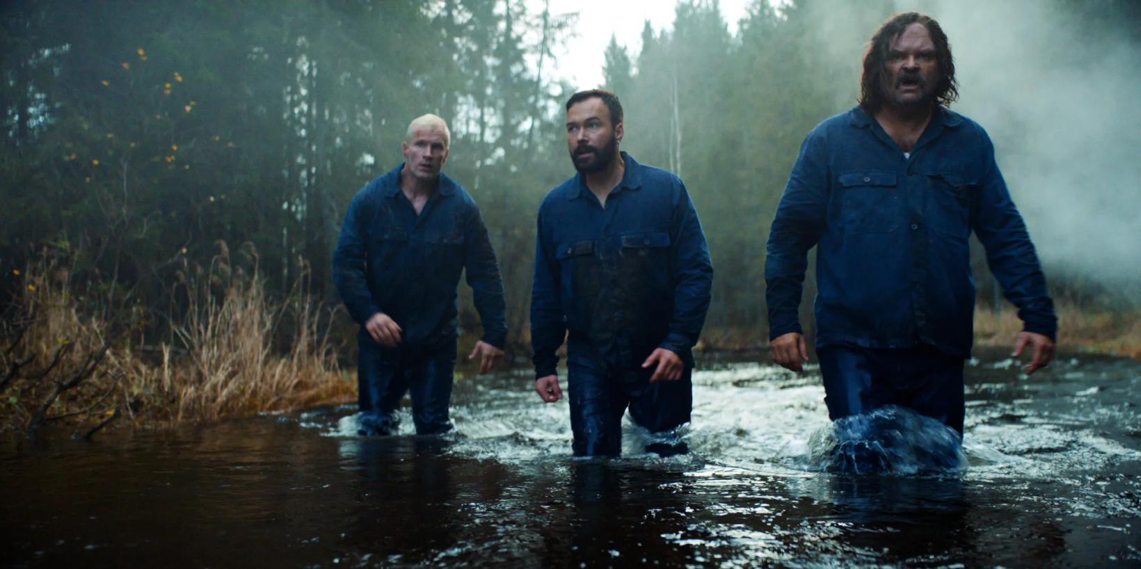 a group of men in raincoats standing in water