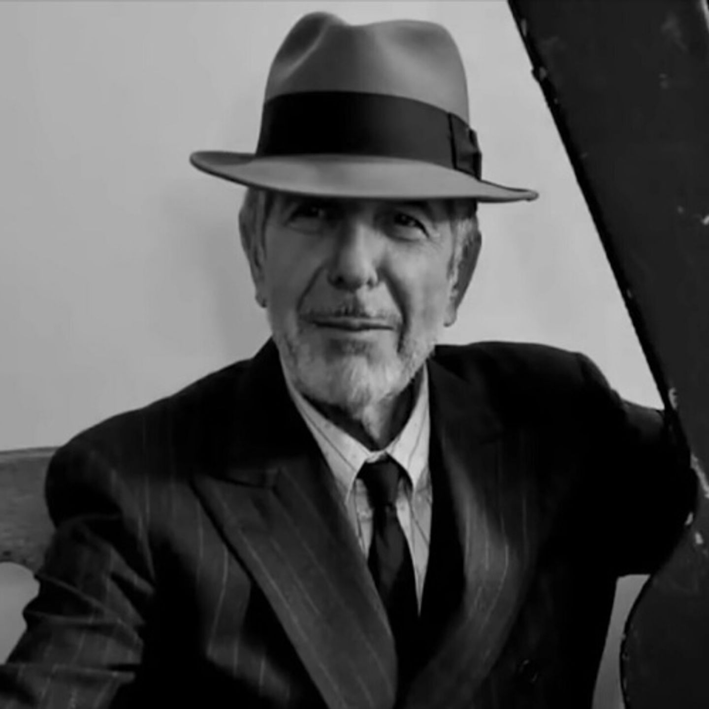 Leonard Cohen in a suit holding a gun