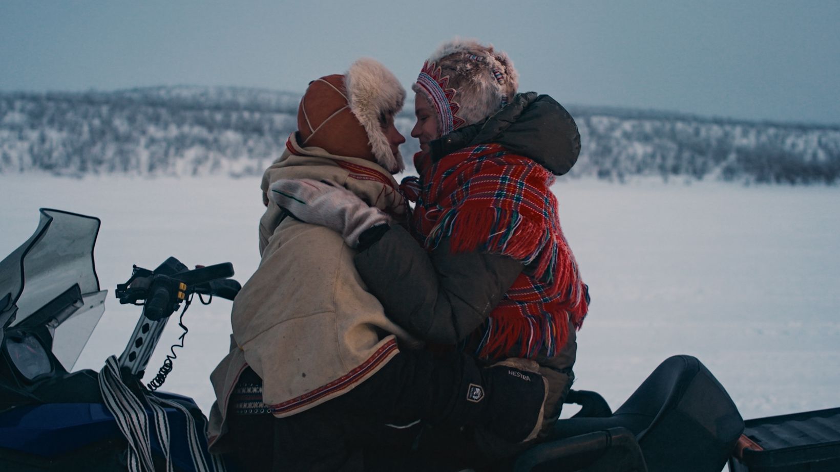 a man and woman sitting on a snowy mountain