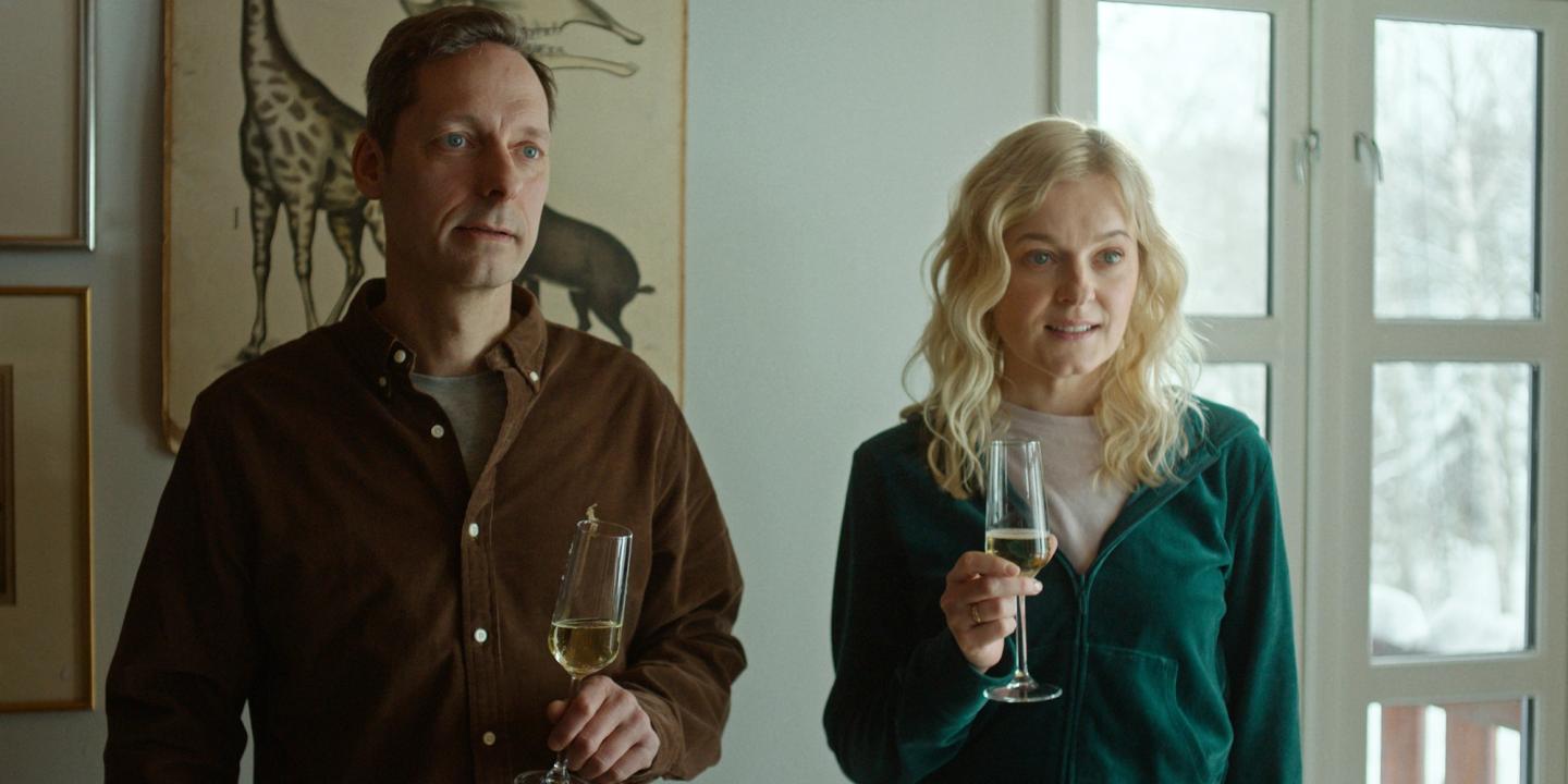 Trond Fausa Aurvåg og Mariann Hole står ved siden av hverandre med et glass hvitvin i hånda i Max-serien MILF of Norway