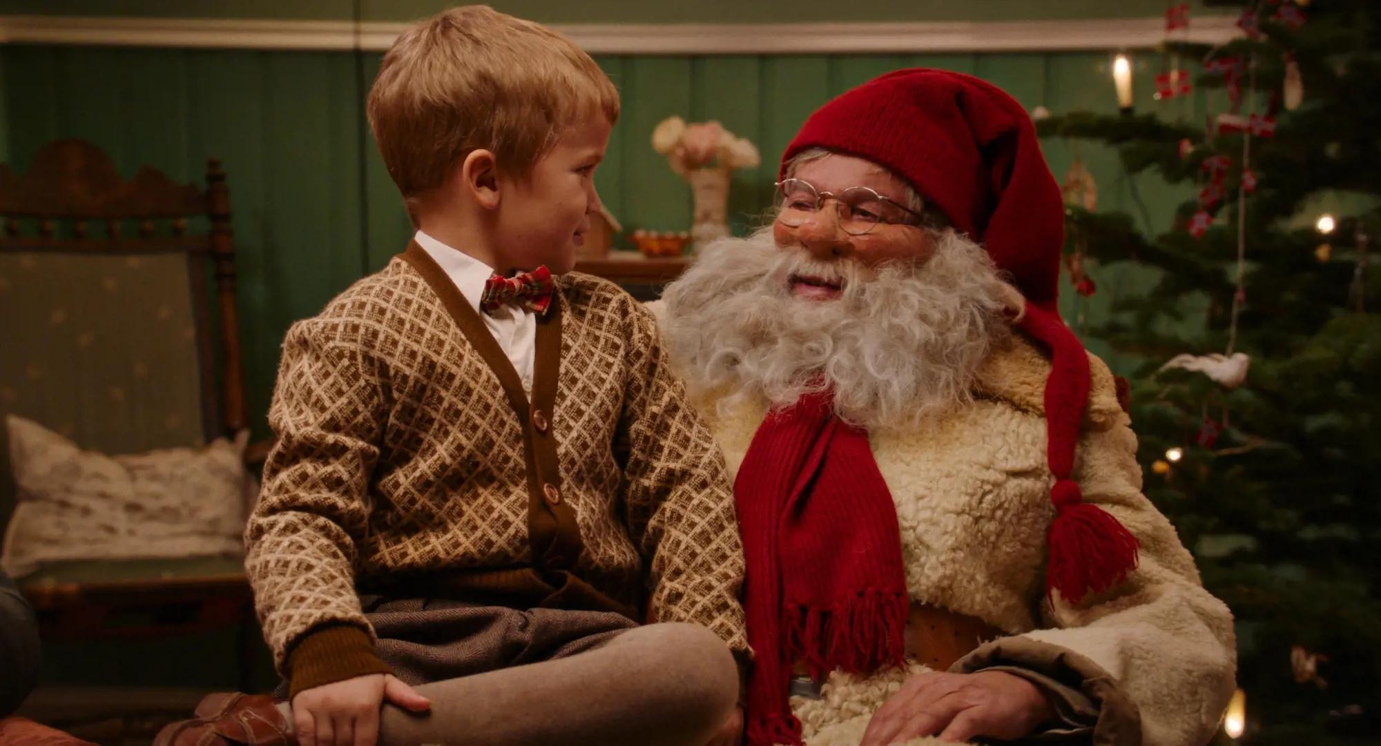 a boy sitting next to a santa claus