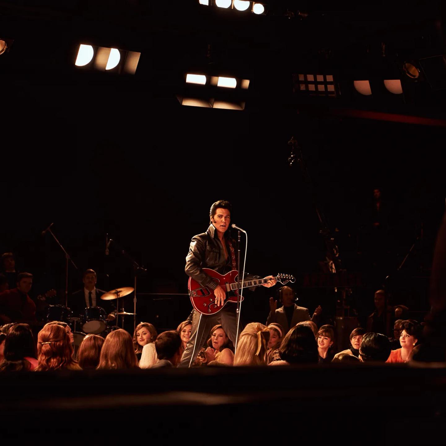 a person playing a guitar on a stage with a crowd watching
