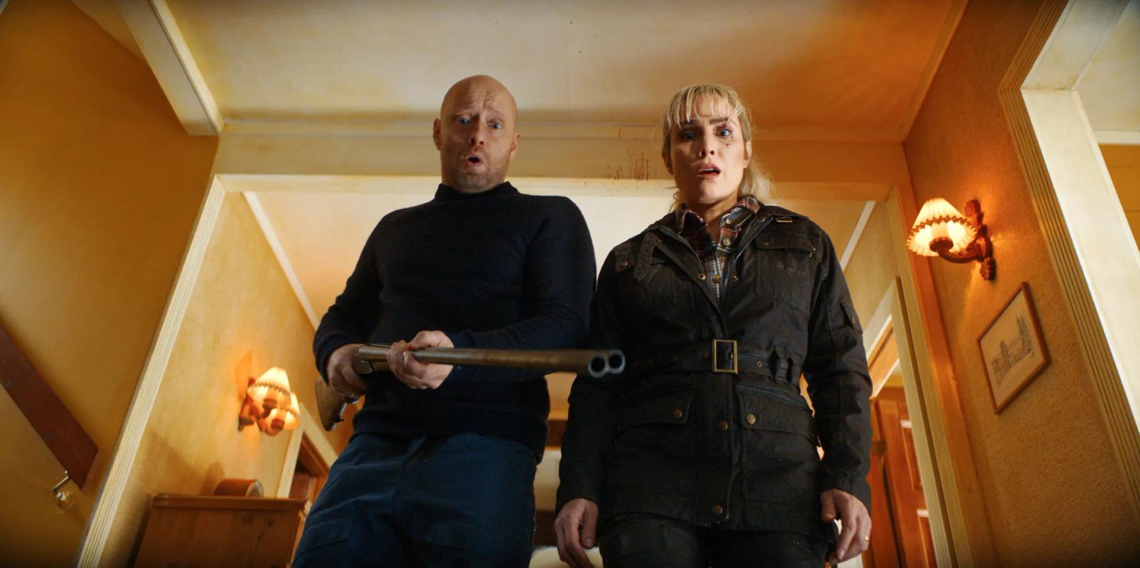 Aksel Hennie and woman holding a gun