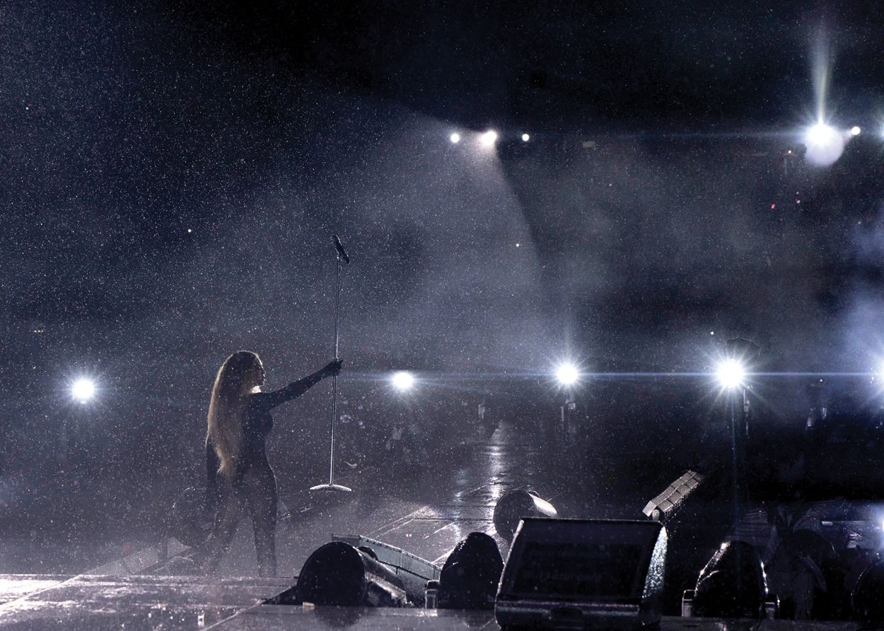 a person on a stage with a microphone and a crowd watching