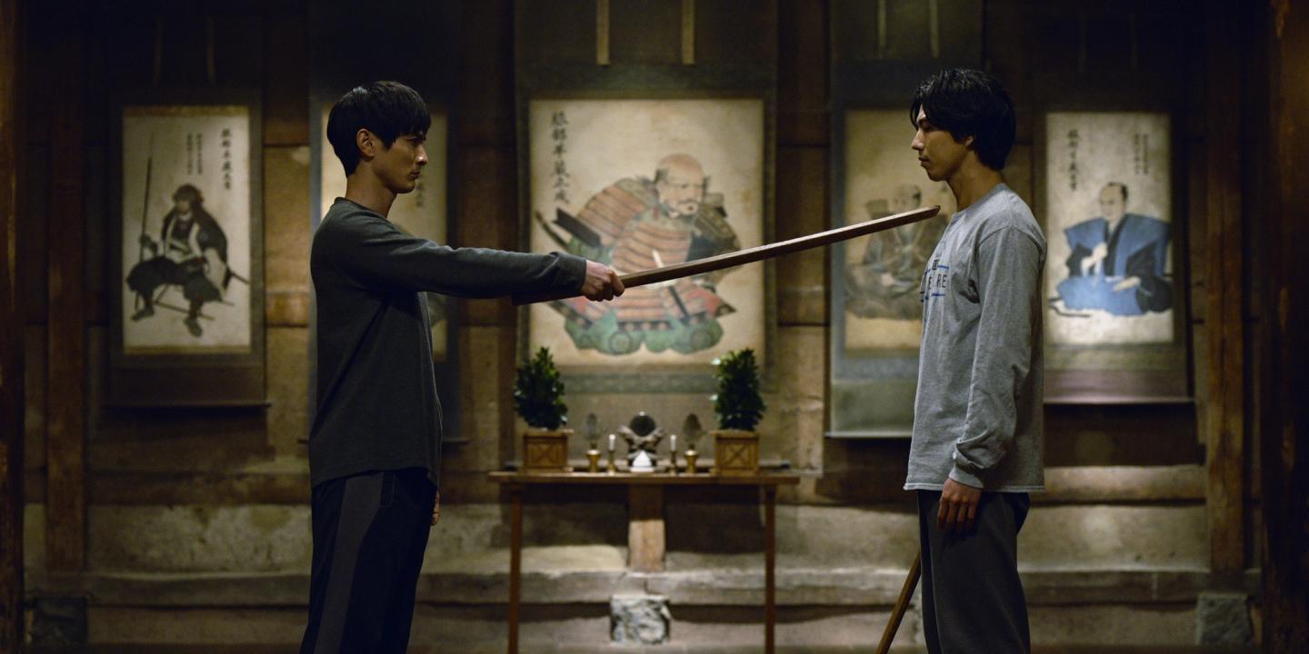 En ung mann peker et tresverd mot strupen til en annen ung mann i serien House of Ninjas