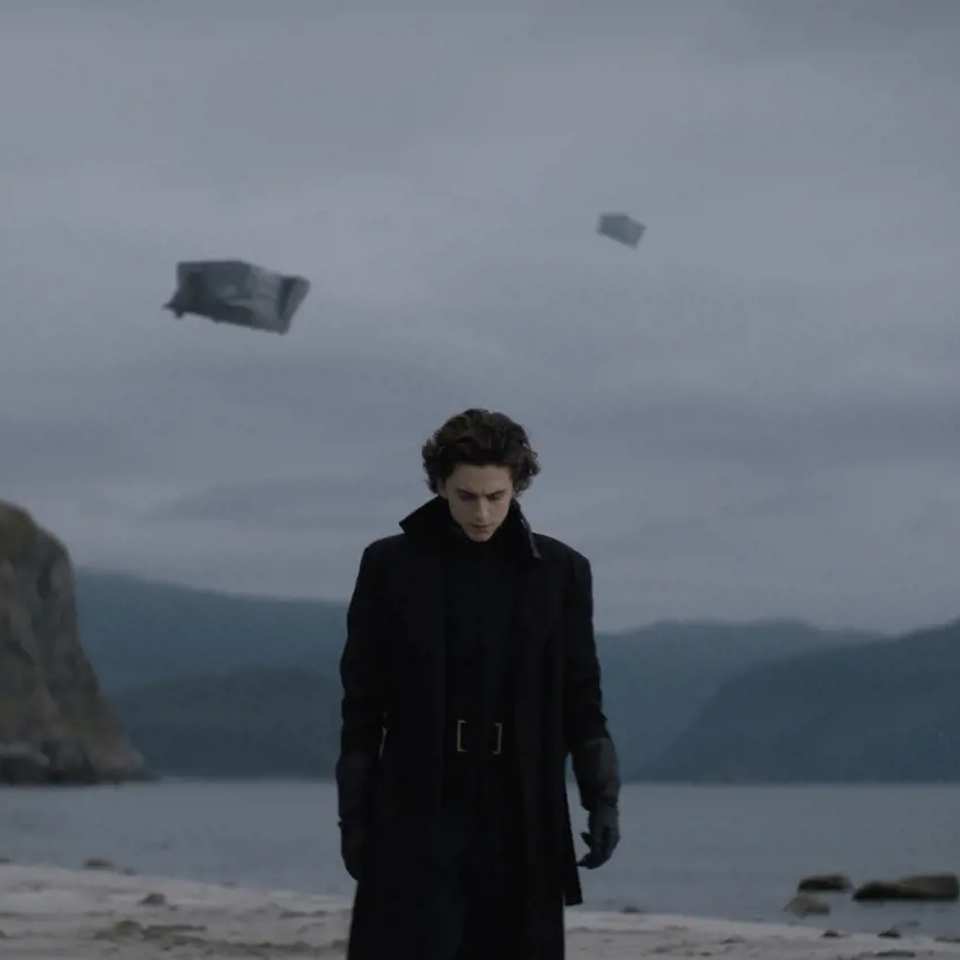 a man standing on a beach with a kite flying in the sky