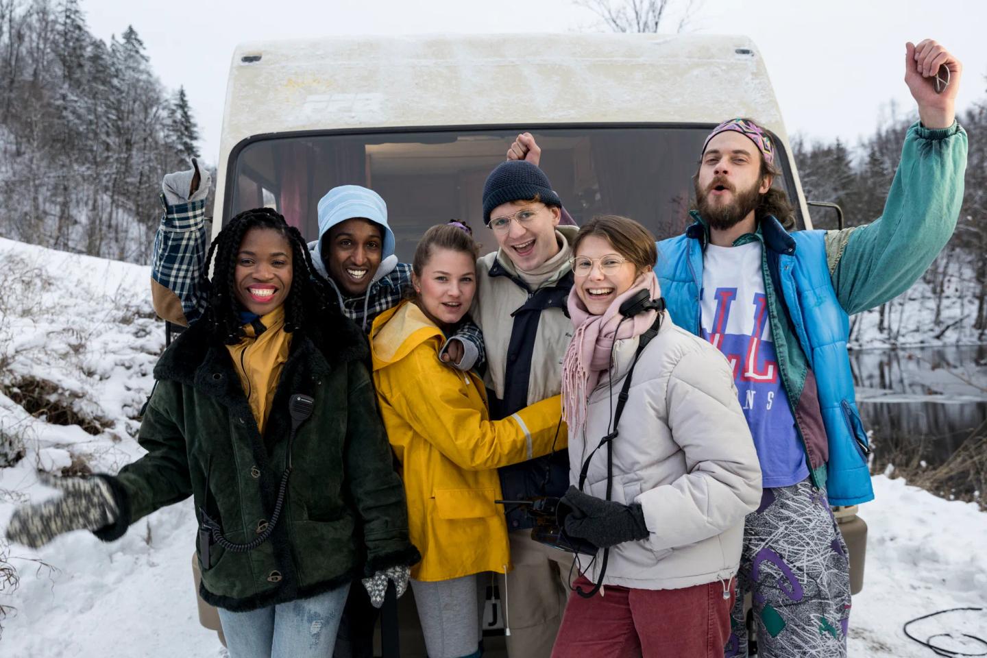a group of people posing for a photo in front of a snow covered bus