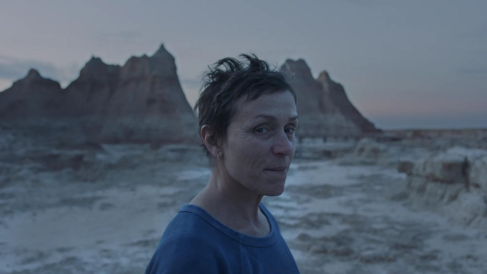 Frances McDormand standing in front of a rocky beach