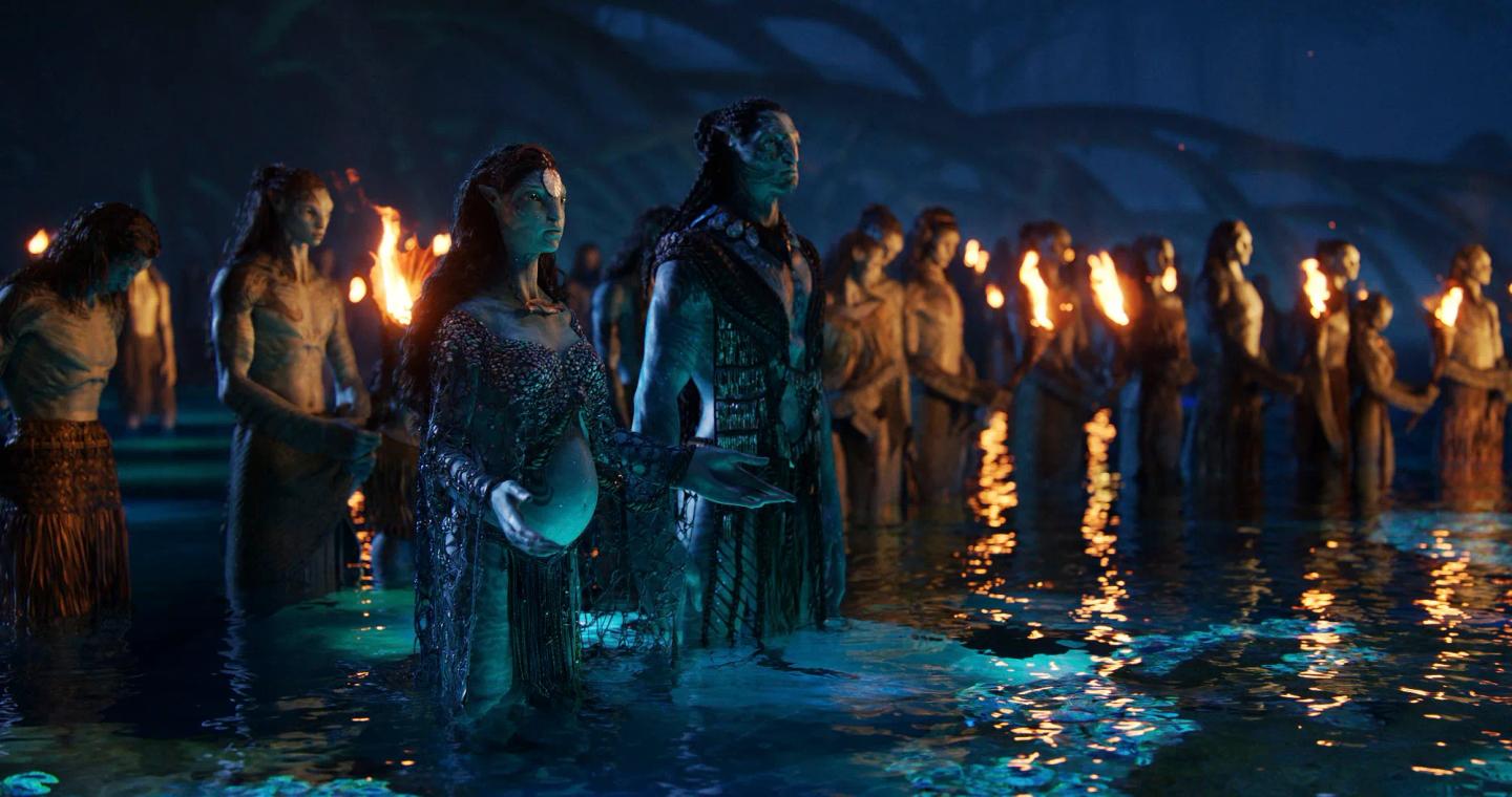 a group of people in clothing standing in water with fire and smoke