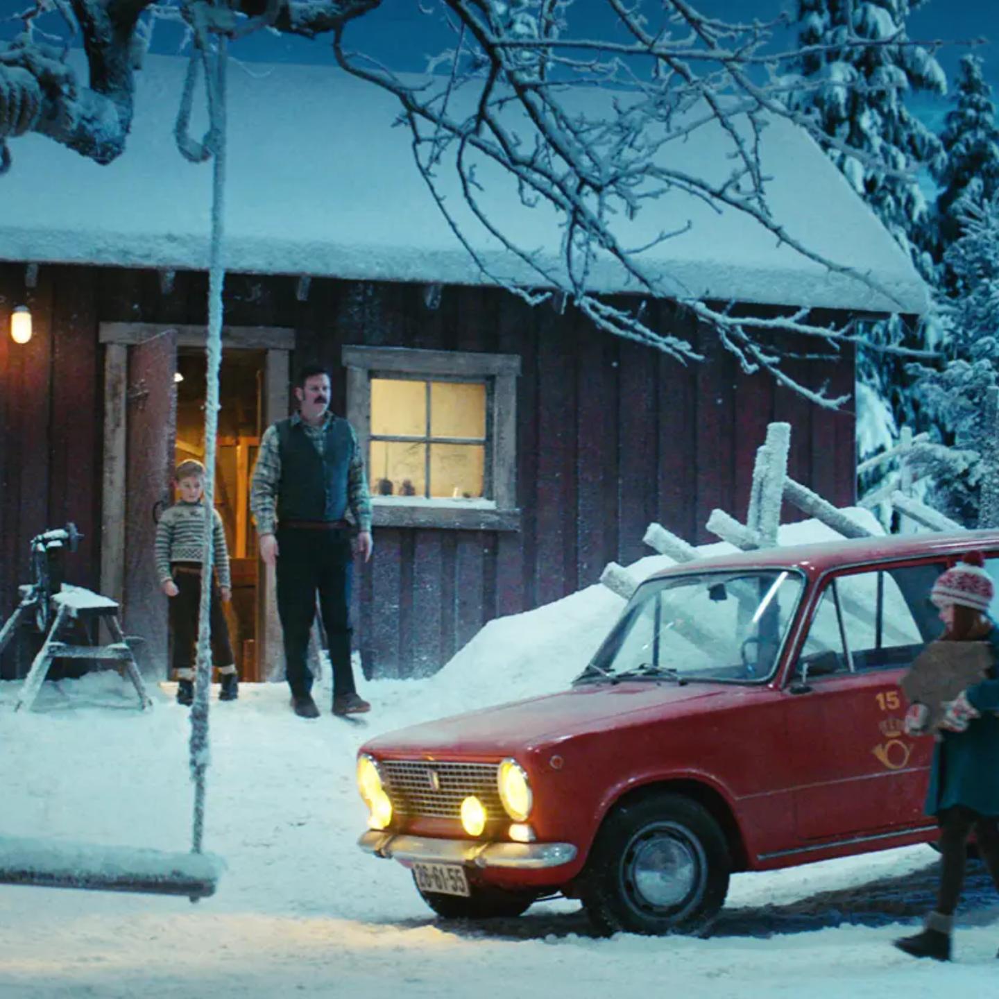 a red truck parked in front of a cabin in the snow