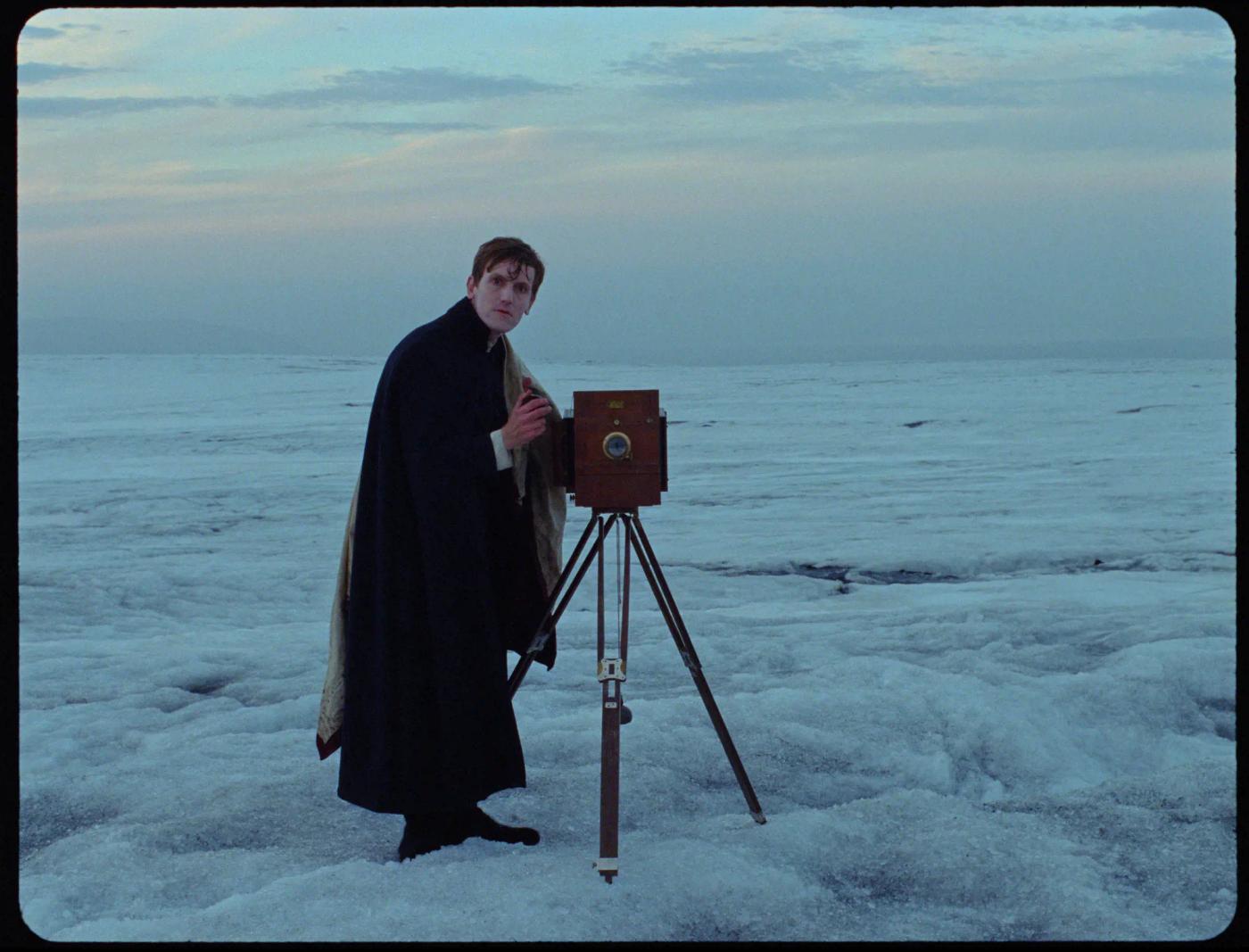 a man standing next to a camera on a beach