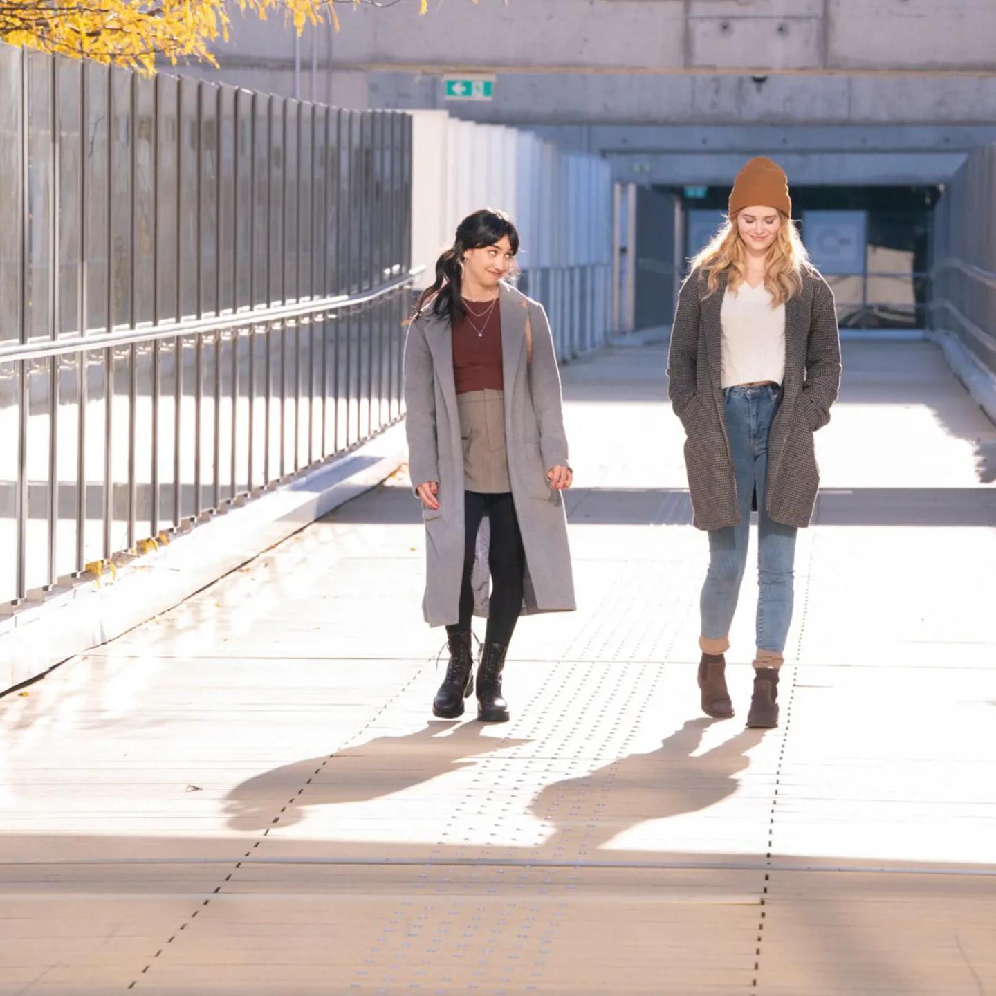 a couple of women walking on a bridge