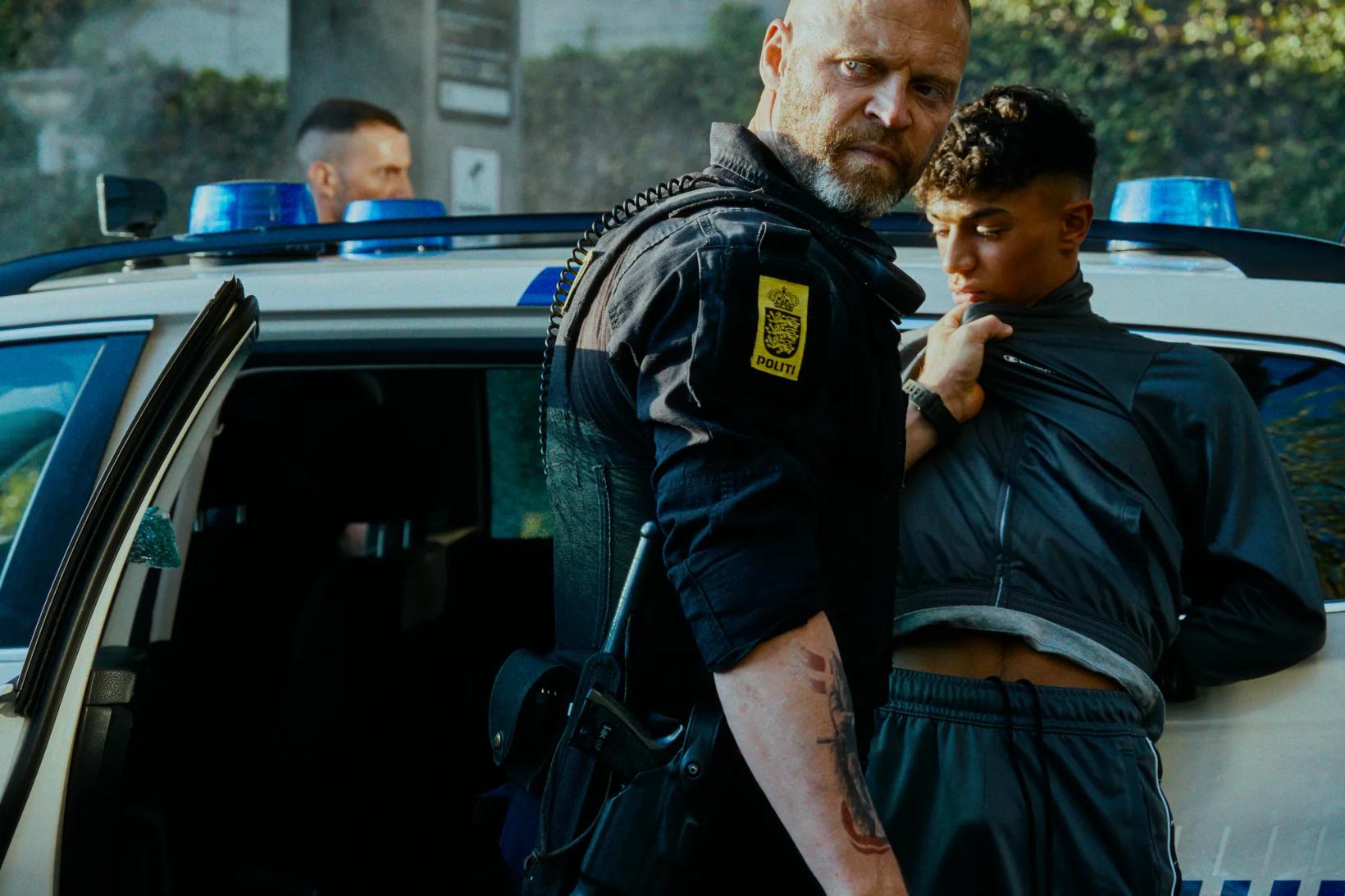 a couple of men in police uniforms standing by a car