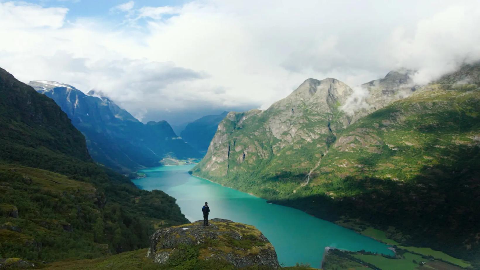 a person standing on a rock overlooking a lake and mountains