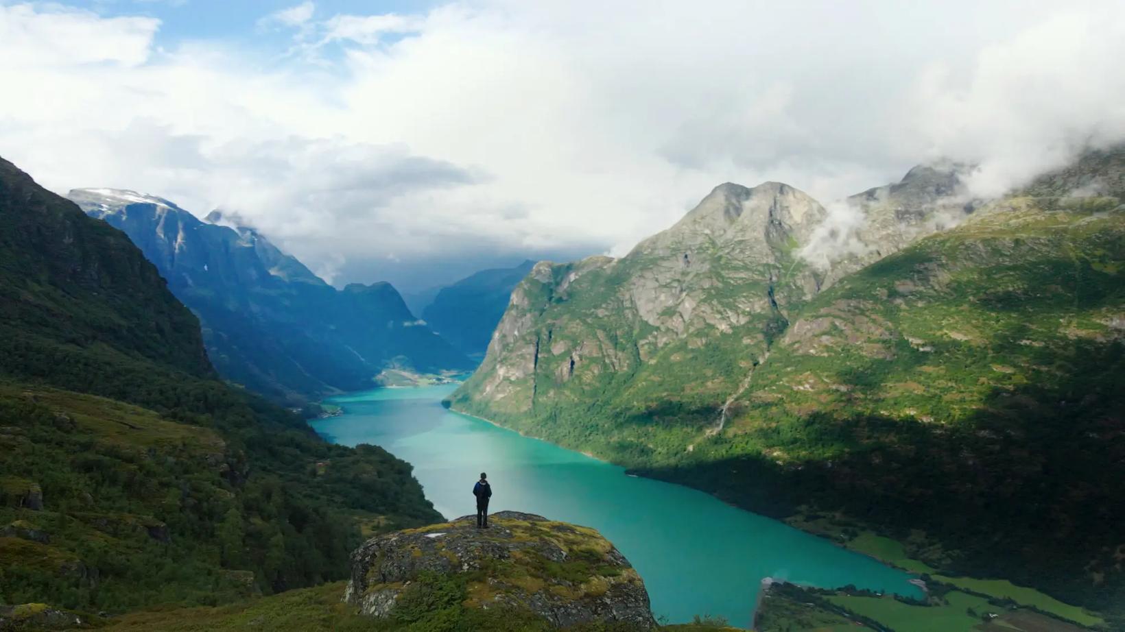 a person standing on a rock overlooking a lake and mountains