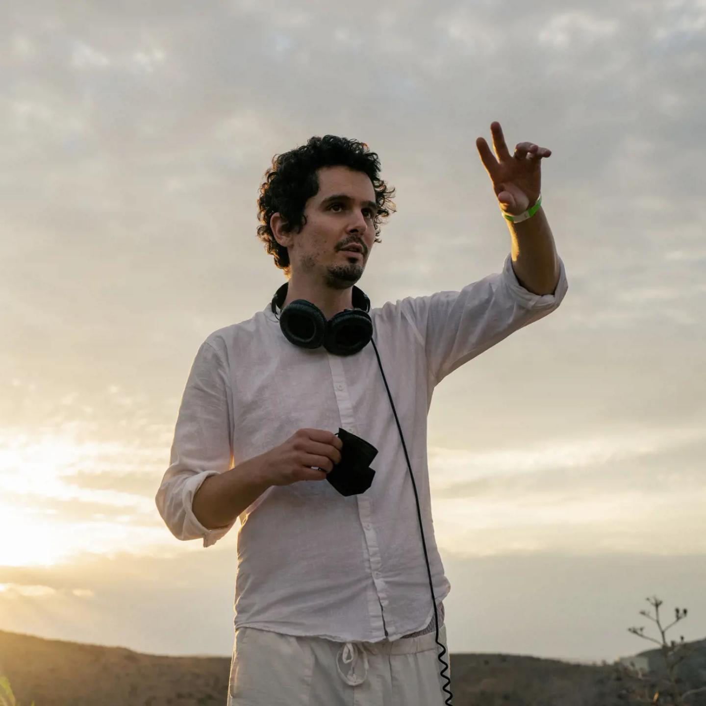 Damien Chazelle wearing headphones and standing next to a traffic light