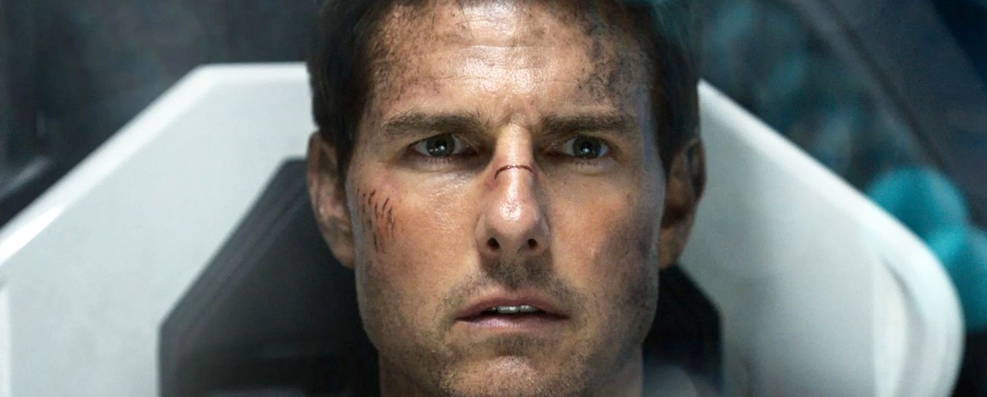 Tom Cruise, med møkk og skrammer i ansiktet, ser rett i kamera.
