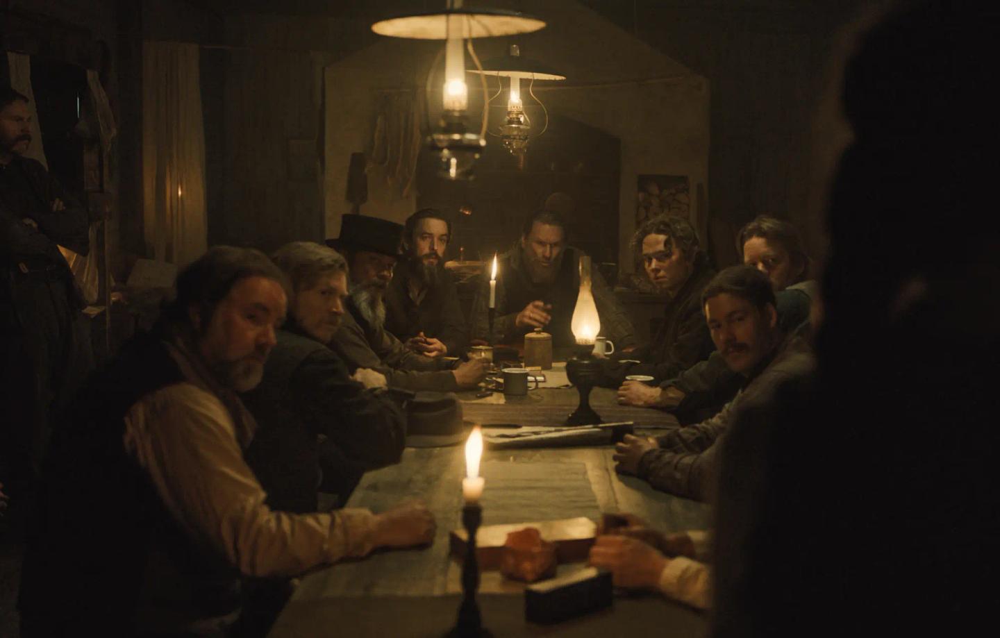 a group of people sitting around a table with candles