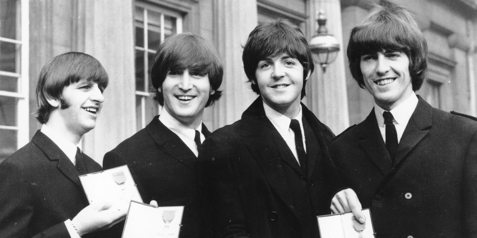 Ringo Starr, John Lennon, Paul McCartney og George Harrison smiler til kamera utenfor Buckingham Palace, England, 26. oktober 1965.