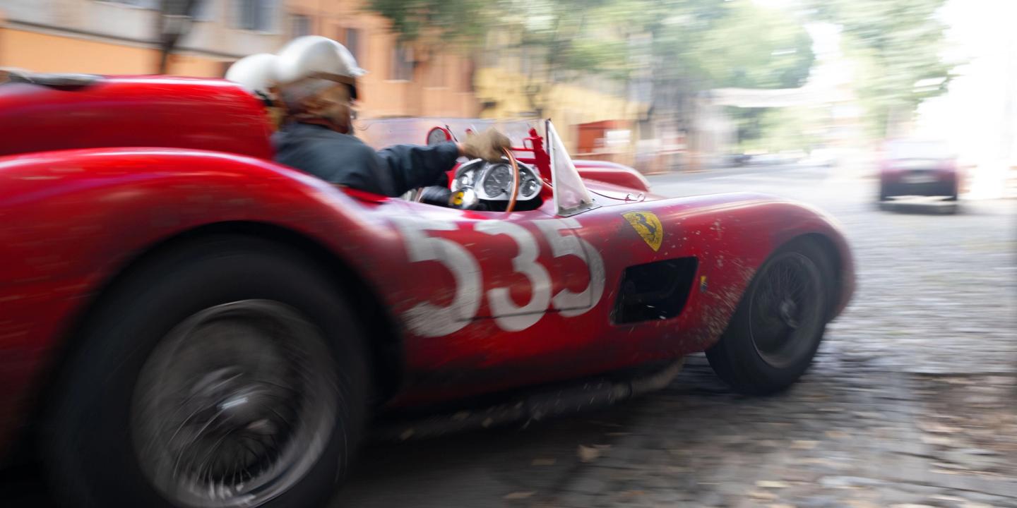 En rød racerbil fra 1957 med nummeret 535 kjører raskt inn i en sving i filmen Ferrari.
