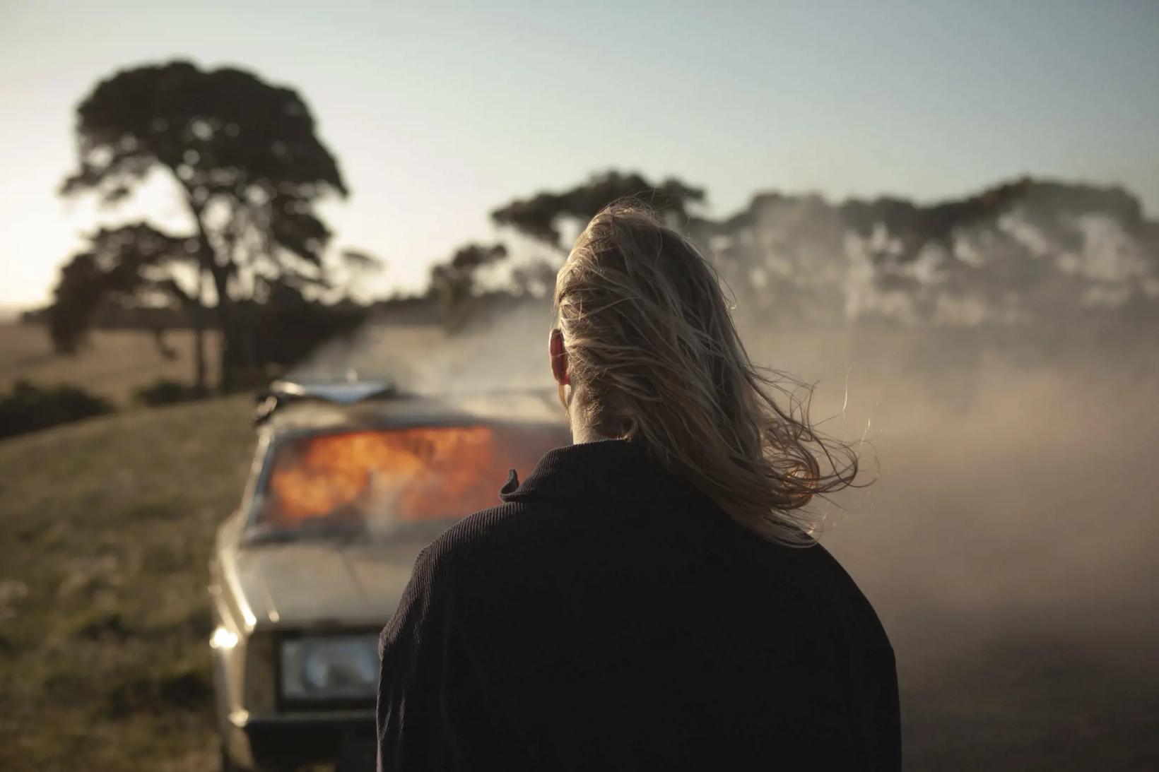 a person standing in front of a car in a foggy field