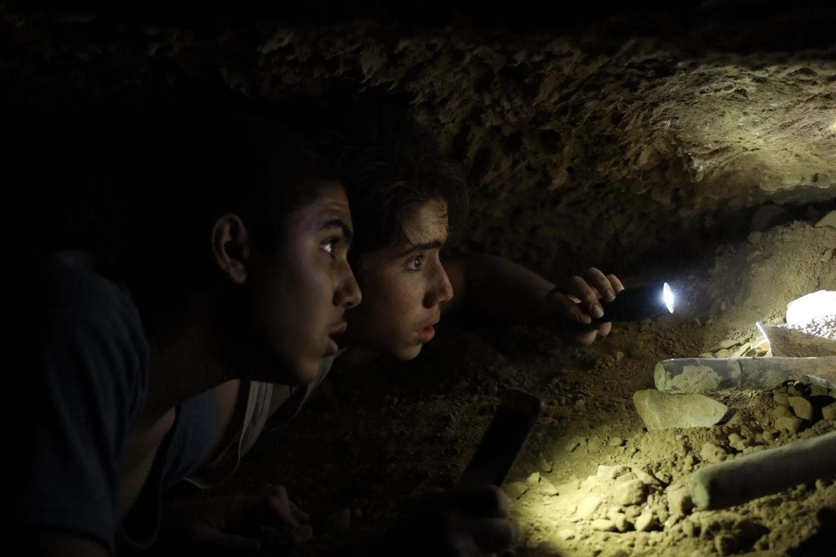 a couple of men looking at a cave