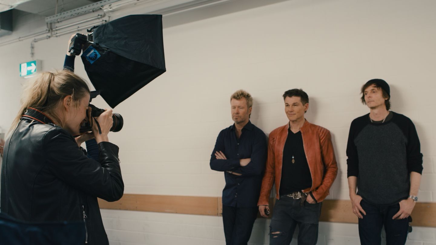 Morten Harket, Paul Waaktaar-Savoy, Magne Furuholmen standing in a room with a camera on the wall