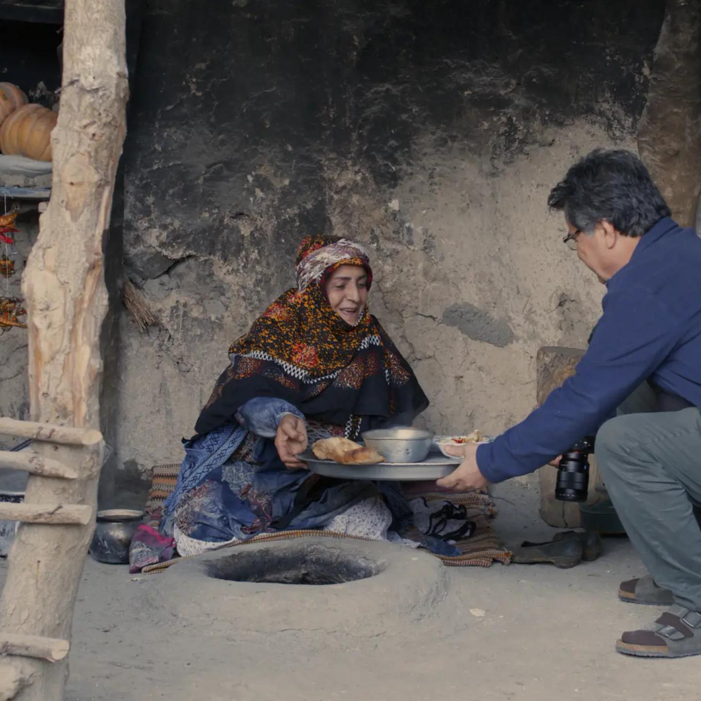 a man and woman sitting on the ground eating food