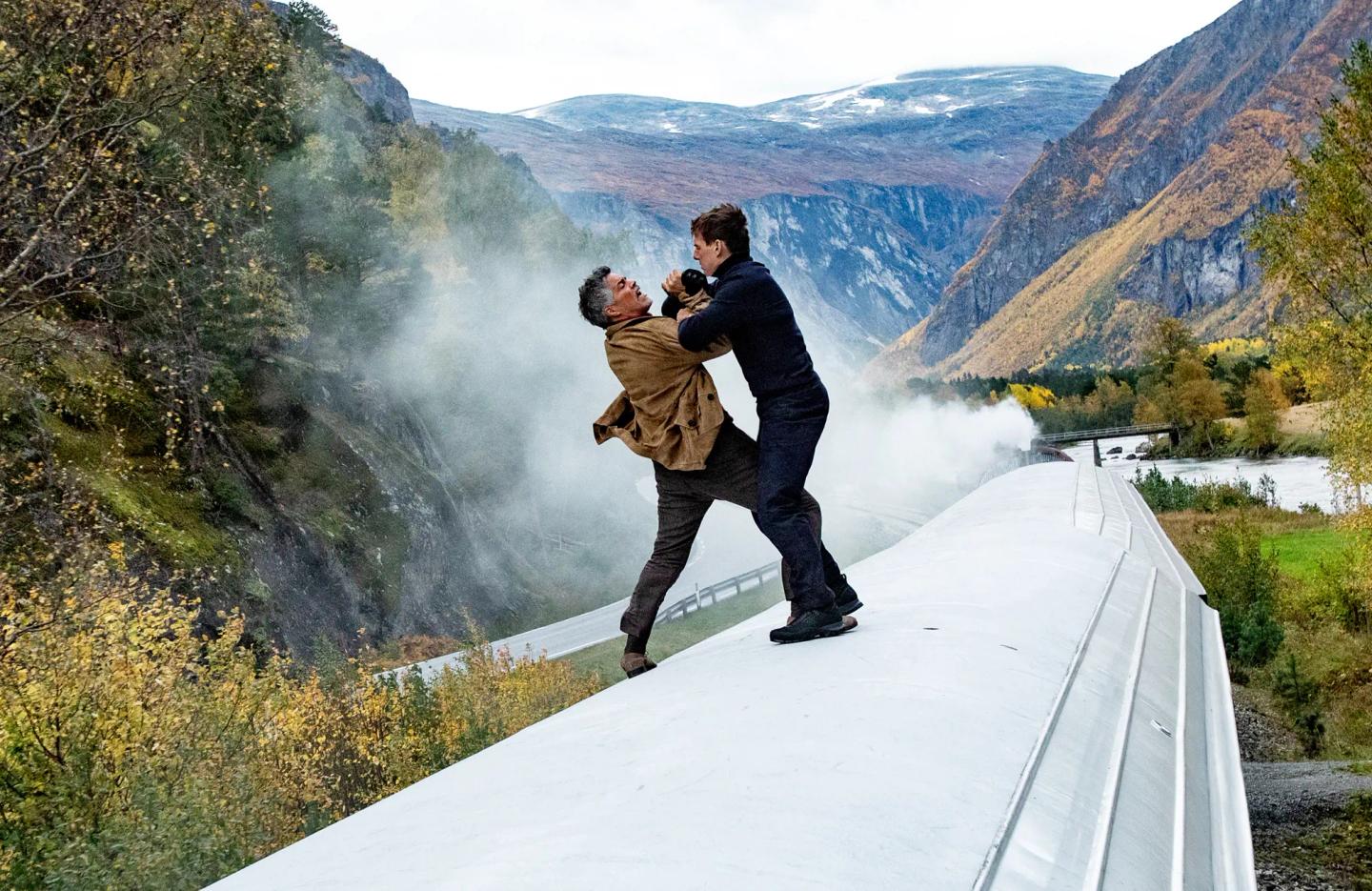 a man and woman kissing on a bridge over a river