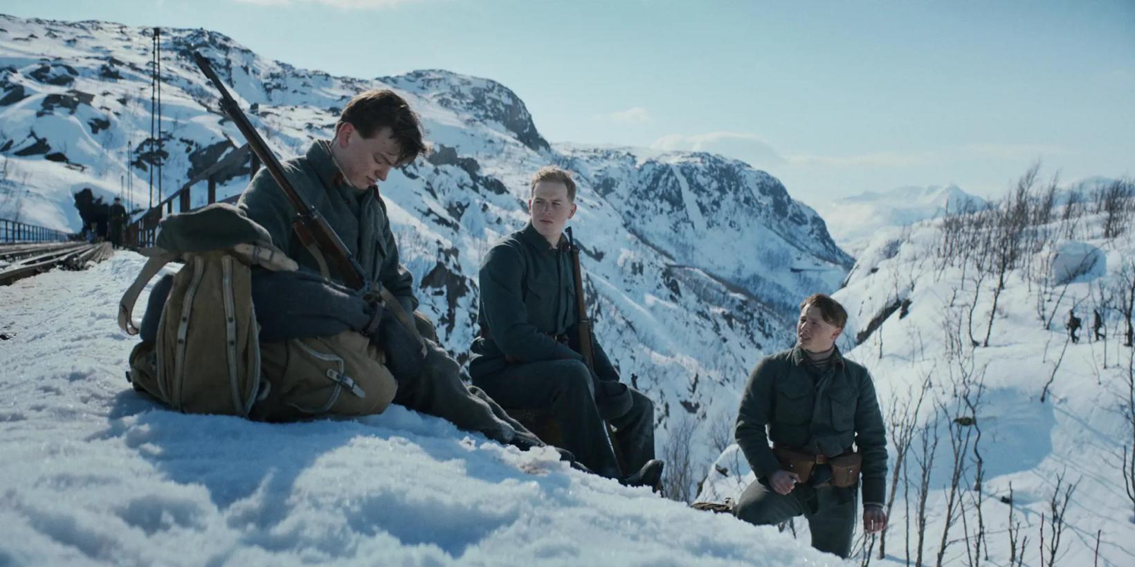 a group of people sitting on a snowy mountain with a rifle