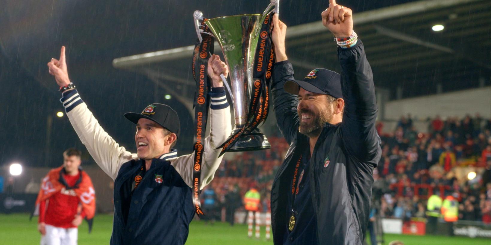 Rob McElhenney og Ryan Reynolds løfter en pokal i Welcome to Wrexham sesong 3