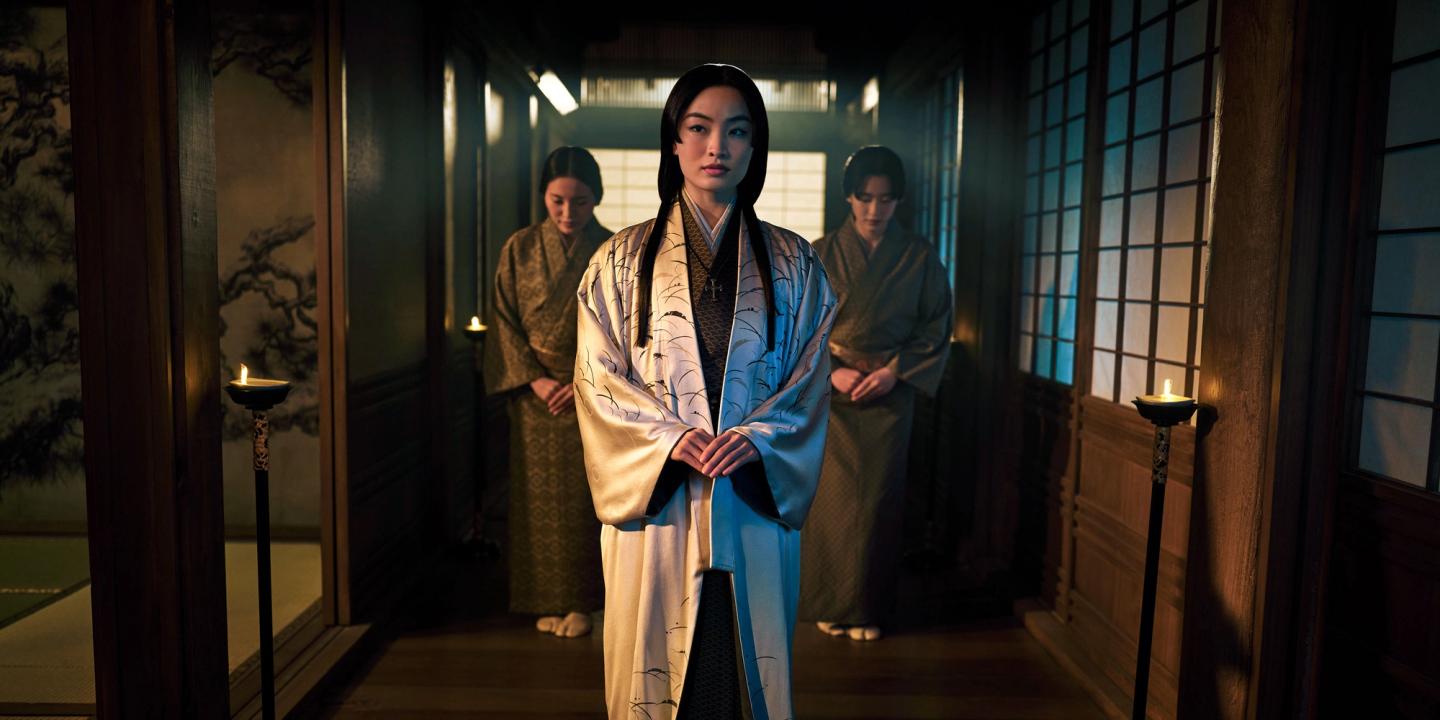 Anna Sawai, iført en kimono og etterfulgt av to andre kvinner, går gjennom en gang i serien Shōgun.