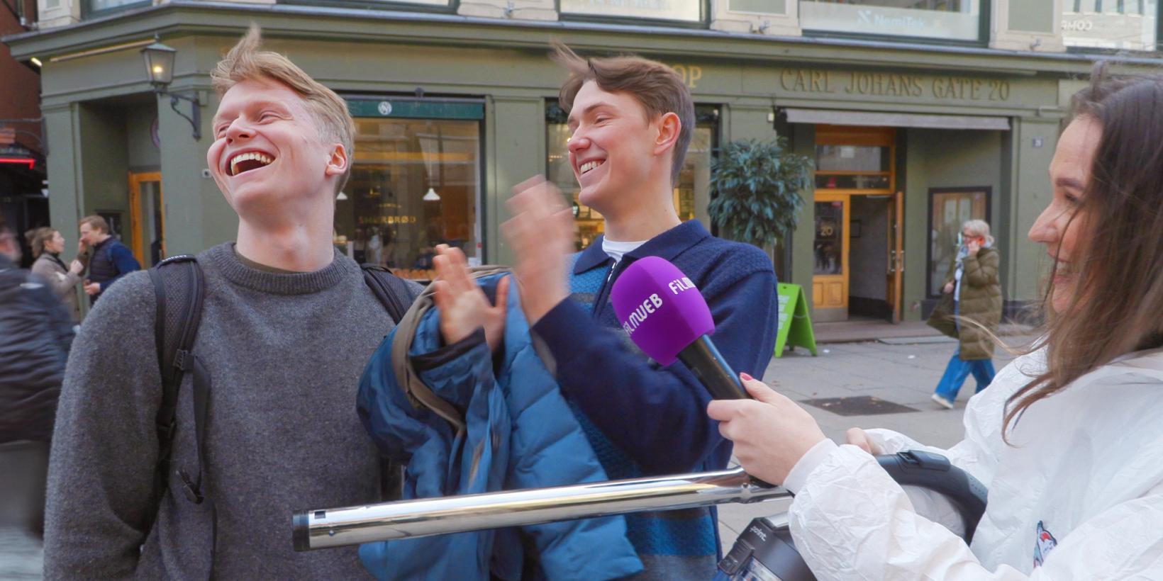 To unge menn applauderer og ler mens Marita fra Filmweb overrekker dem en støvsuger.