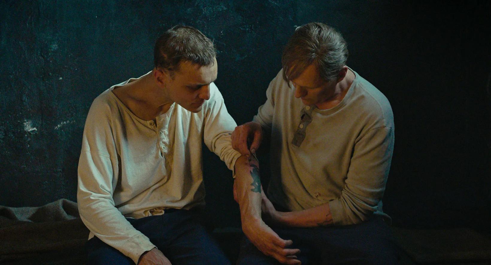 a couple of men sitting on a bed
