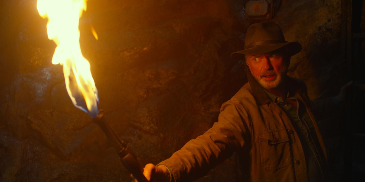 a man in a hat holding a gun in front of a fire