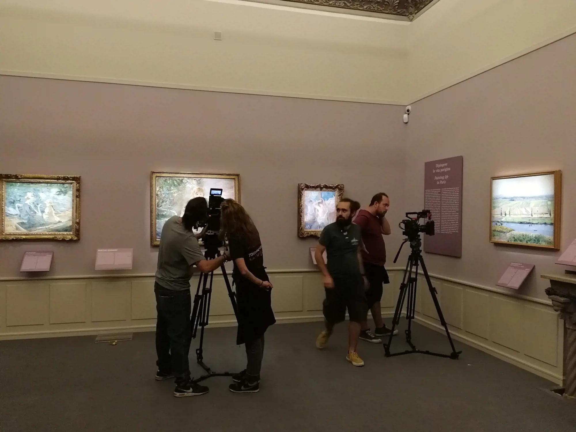 a group of people standing in a room with cameras and pictures on the wall
