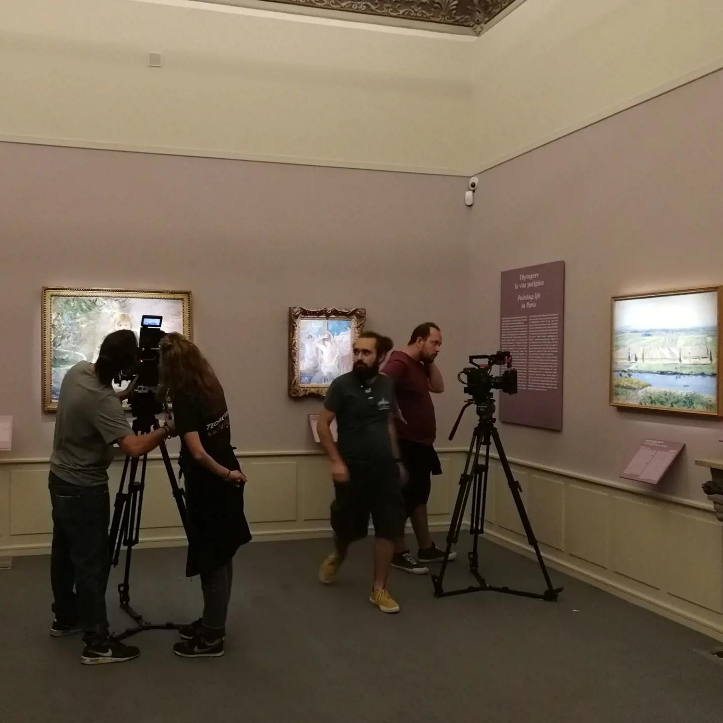a group of people standing in a room with cameras and pictures on the wall