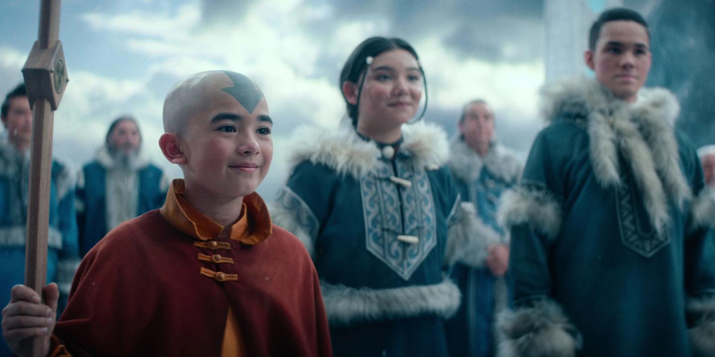 Aang (Gordon Cormier), Katara (Kiawentiio) og Sokka (Ian Ousley) ser stolt mot siden, med en folkemengde bak seg, i live-action-serien Avatar: The Last Airbender sesong 1
