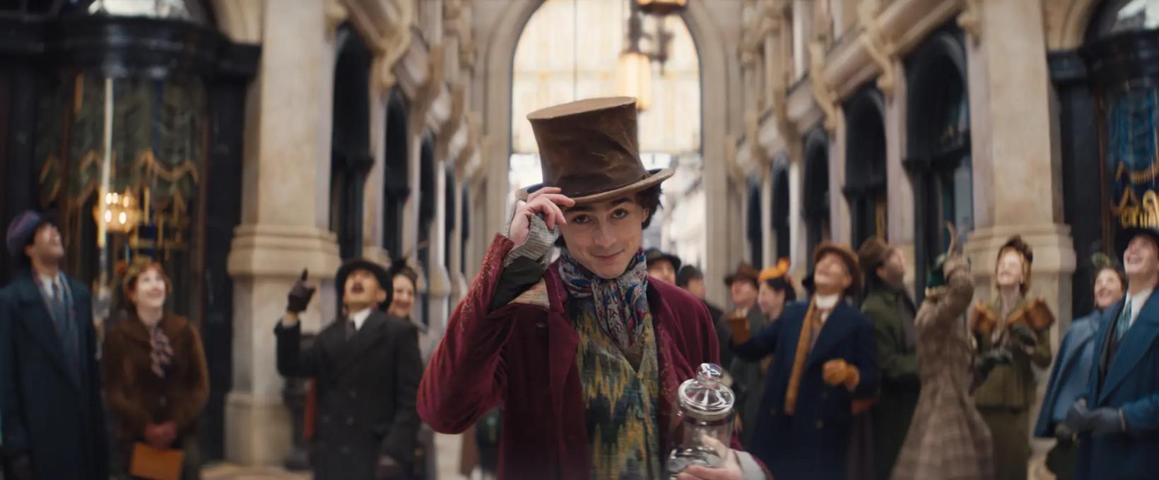 a person in a hat and coat holding a trophy in a crowded room