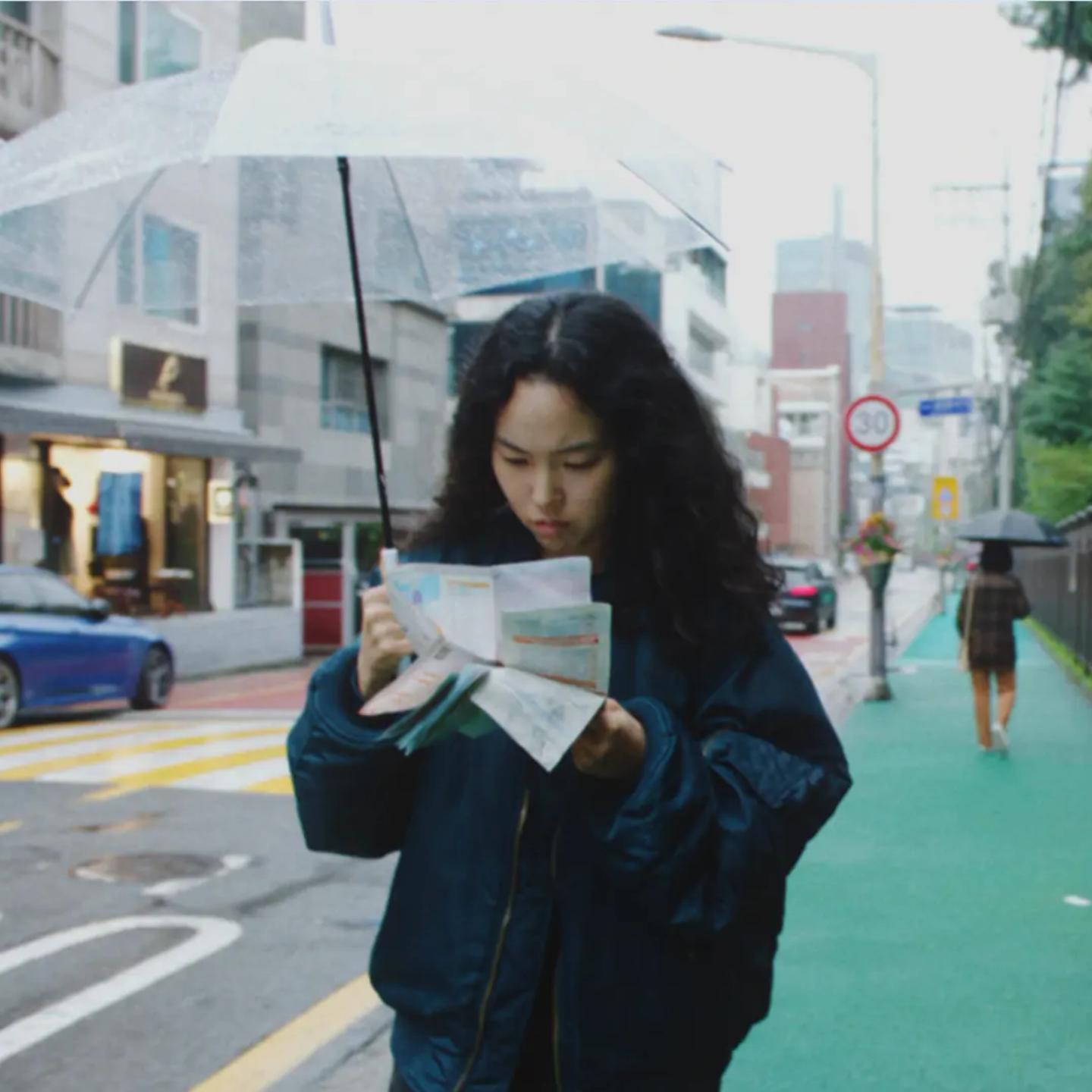 a woman reading a newspaper on a sidewalk