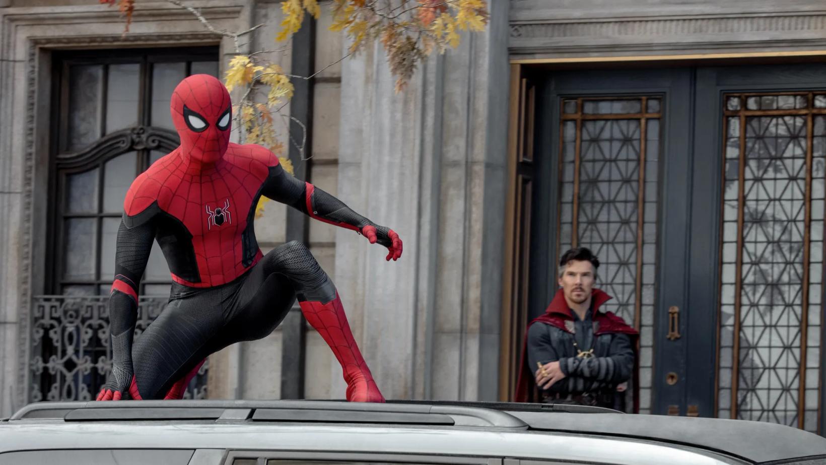 Benedict Cumberbatch in a garment sitting on a car next to a person