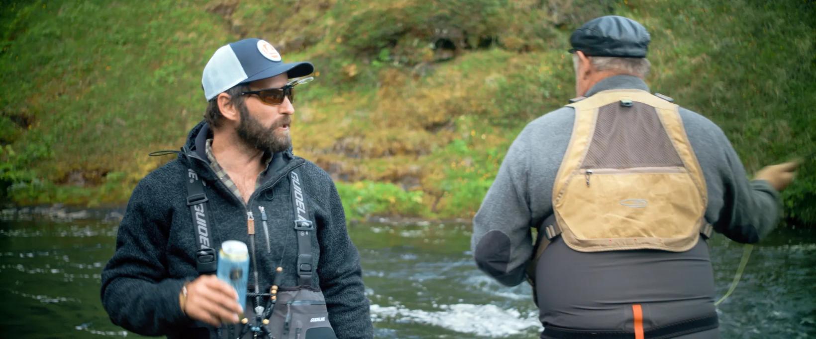 two men standing in front of a river