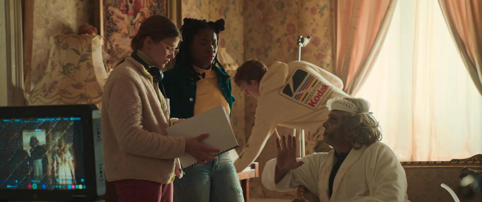 a group of people standing in a room with a television and a person holding a box