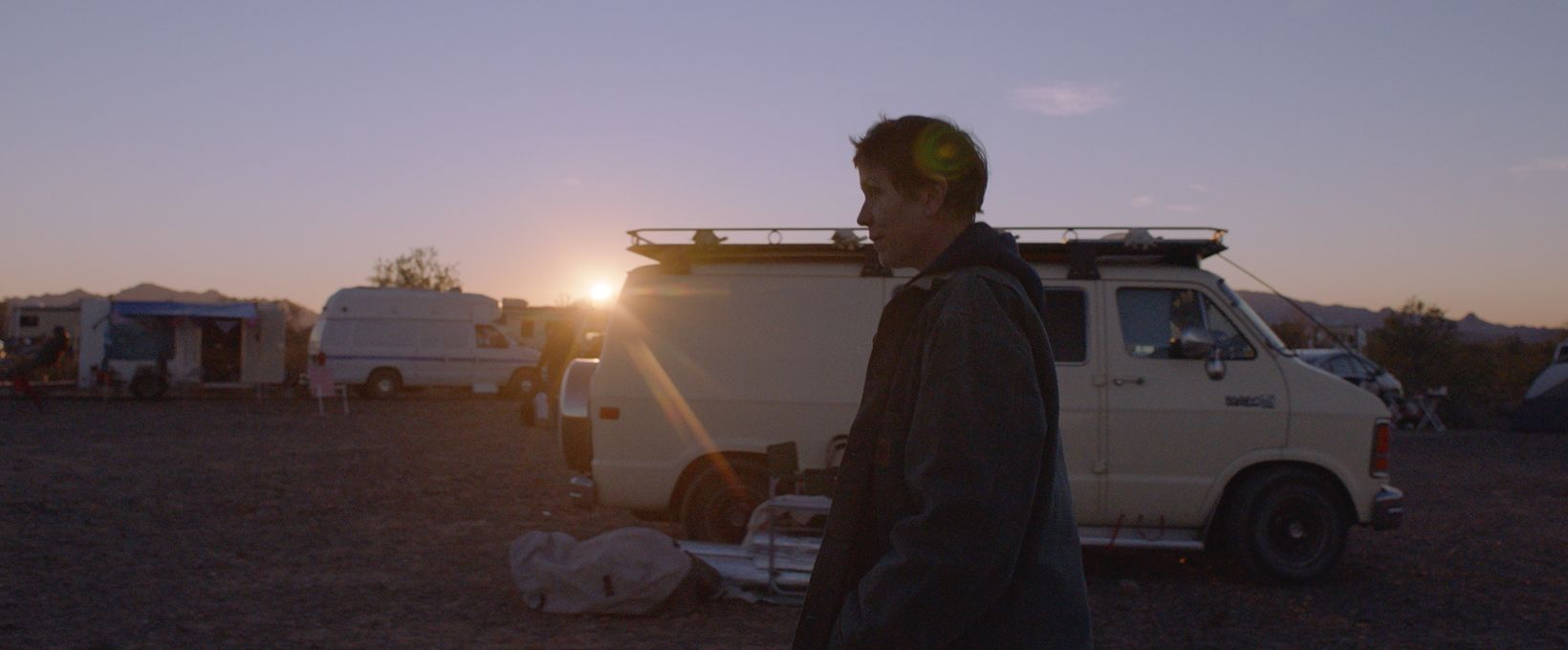a man with a gun in his hand standing in front of a white truck