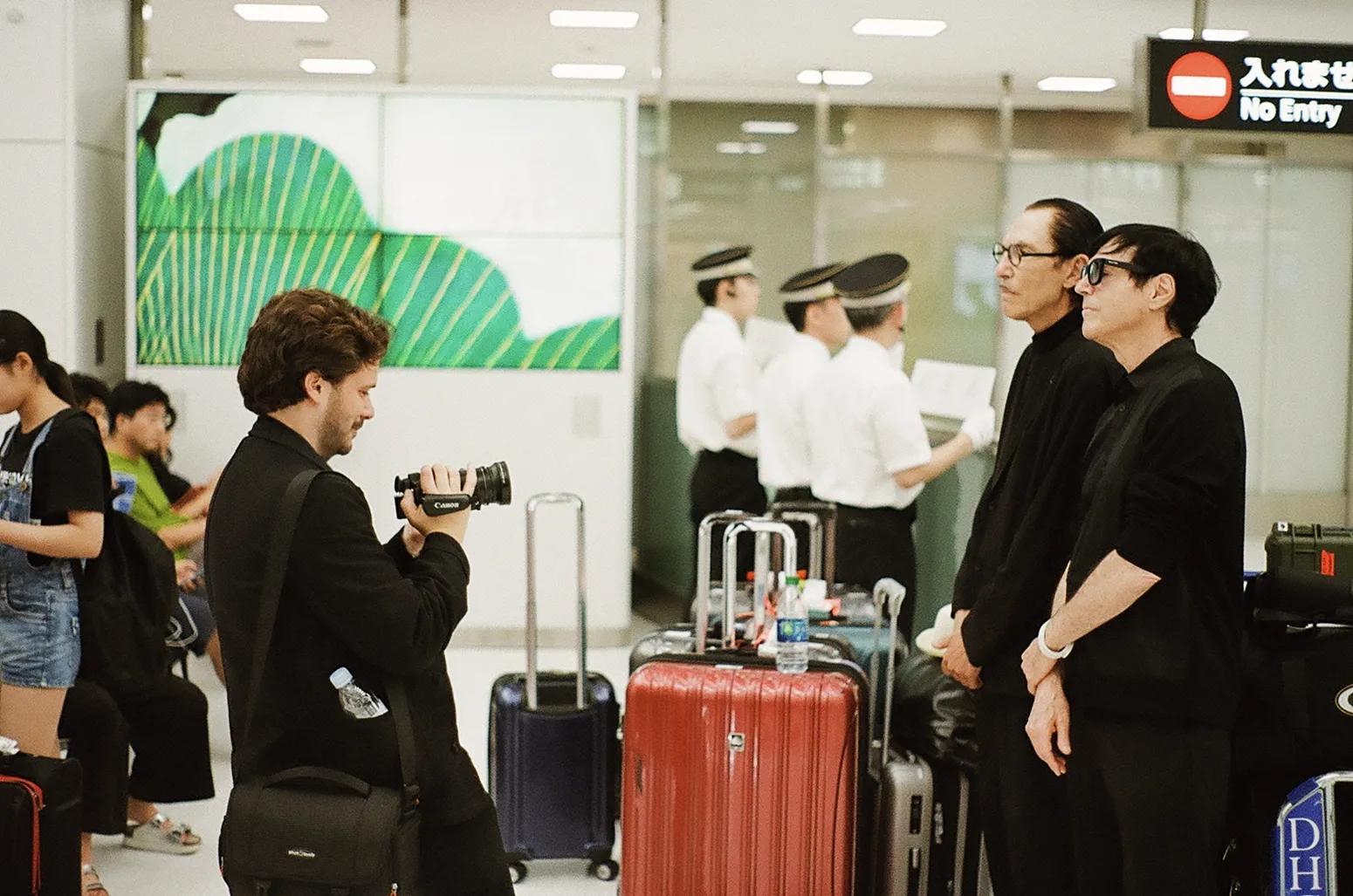 Ron Mael taking a picture of a person with a camera